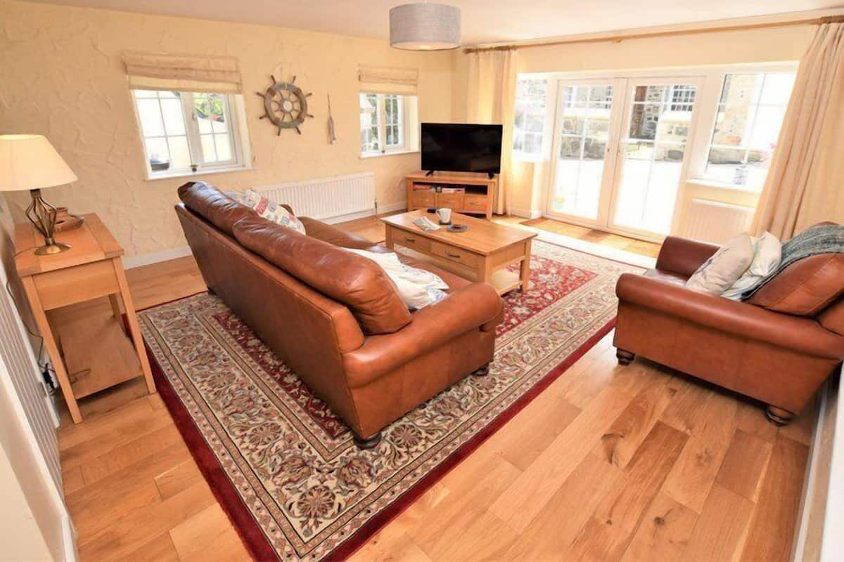 A living room with two leather sofas, a wooden coffee table, a TV, and a patterned rug.