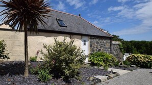 A stone house with a sloped roof, a small window, and a door.