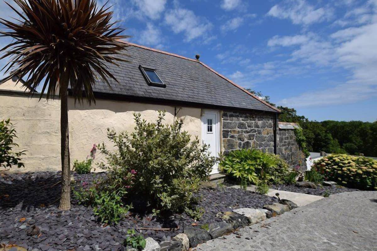 A stone house with a sloped roof, a small window, and a door.