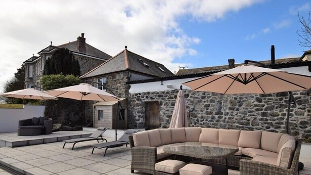 An outdoor seating area with a stone wall, a stone building, and a large umbrella.