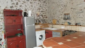 A compact kitchen with a refrigerator, washing machine, stove, and a round table with stools. - Beautiful renovated stone barn with magnificent view! Quiet village (Rabouillet)