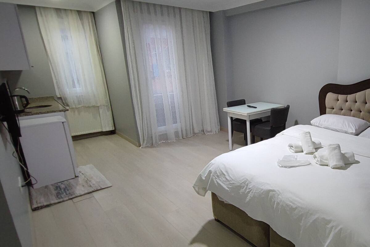 A hotel room with a bed, bedside table, and a small desk with a chair.