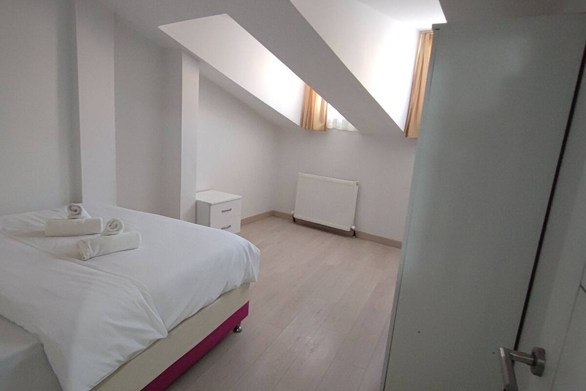 A bedroom with a bed, a nightstand, a radiator, and a door.