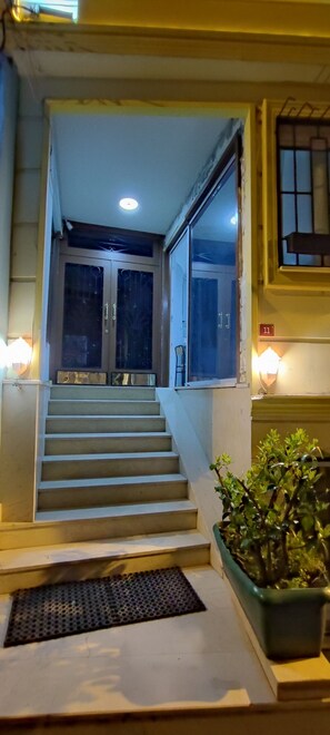A staircase leading to a door with glass panels, a potted plant, and wall-mounted lights. - Sunset Apart (Istanbul)