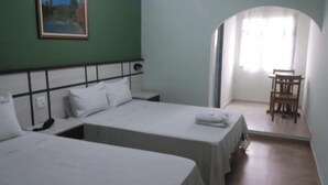 Une chambre d’hôtel avec deux lits simples, un tableau au mur, un climatiseur et un coin repas avec des chaises.