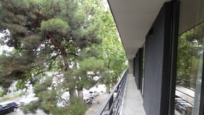 A balcony with a view of parked cars and a tree.