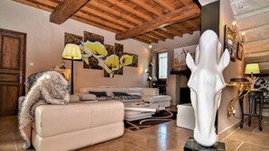 Een woonkamer met een witte bank, een pluizige hond en een groot, wit beeldhouwwerk.