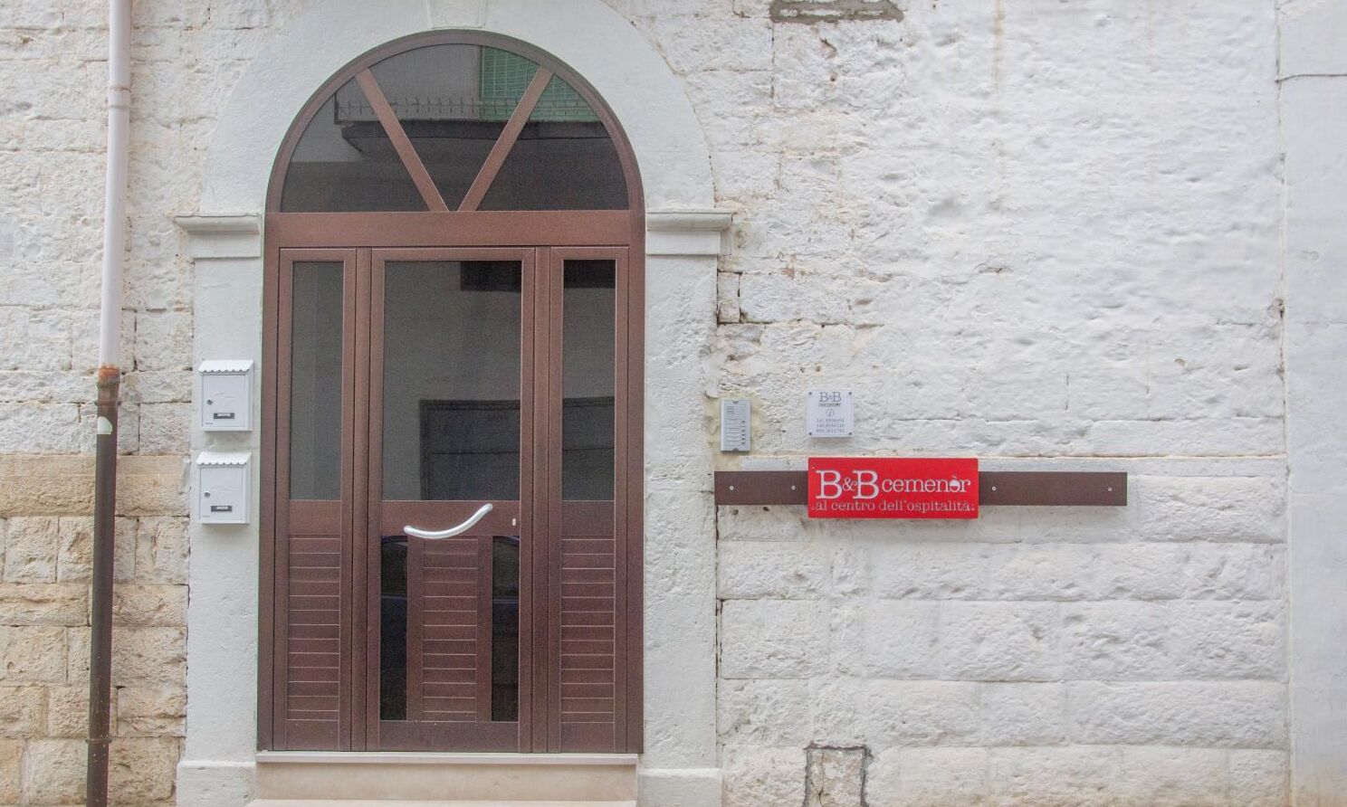 A building entrance with a brown door and a sign indicating 'B&B Cimitero al centro dell'ospitalità'.