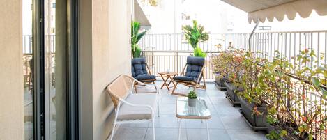 A balcony with two chairs, a small table, and potted plants.