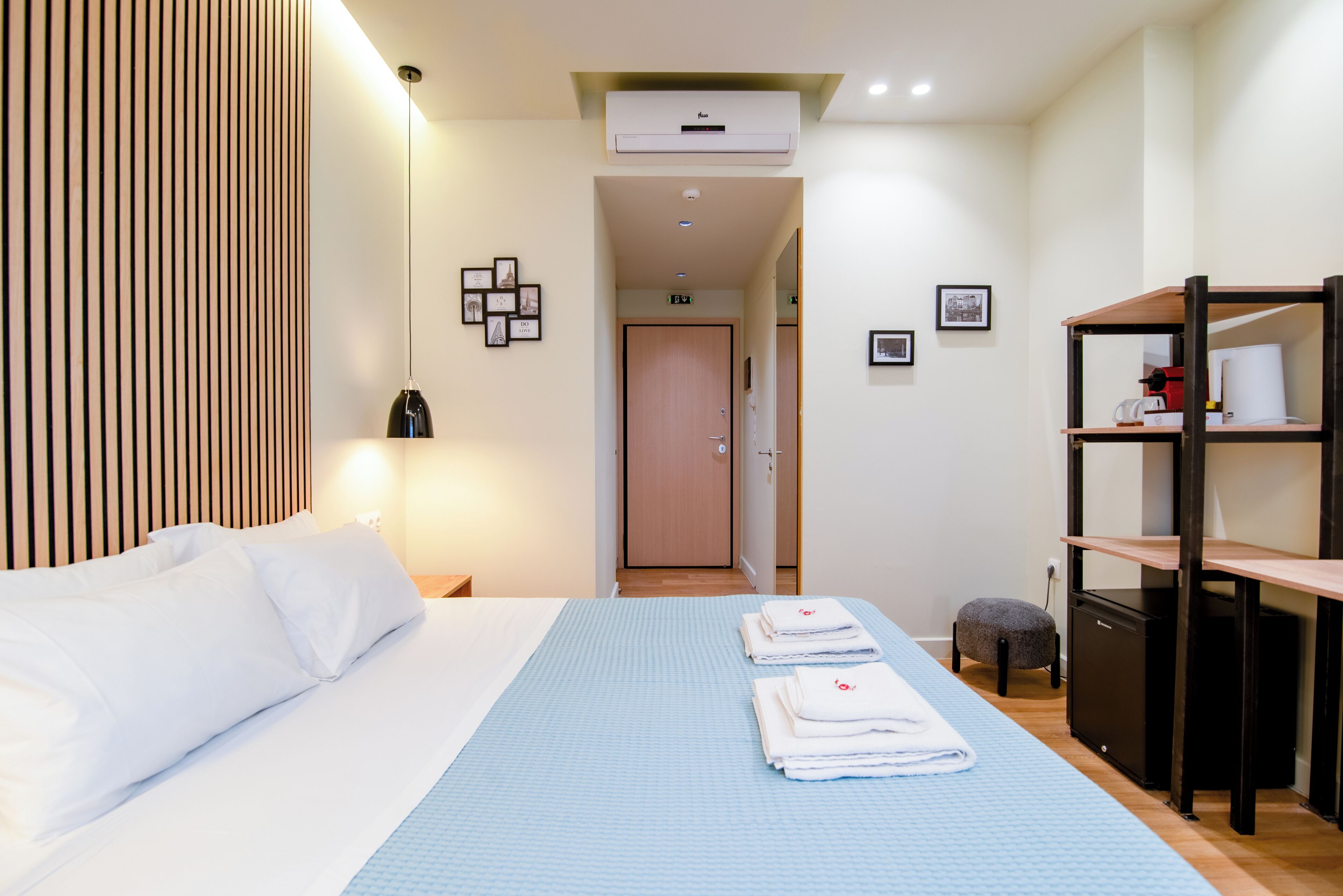 A hotel room with a bed, a desk, a chair, a wardrobe, and a bathroom door.