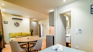Una habitación de hotel moderna con una mesa redonda de comedor, un sofá y una cama con toallas.