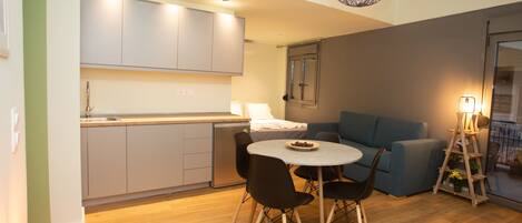 Una cocina moderna con gabinetes grises, una mesa de comedor con sillas y un sofá azul.