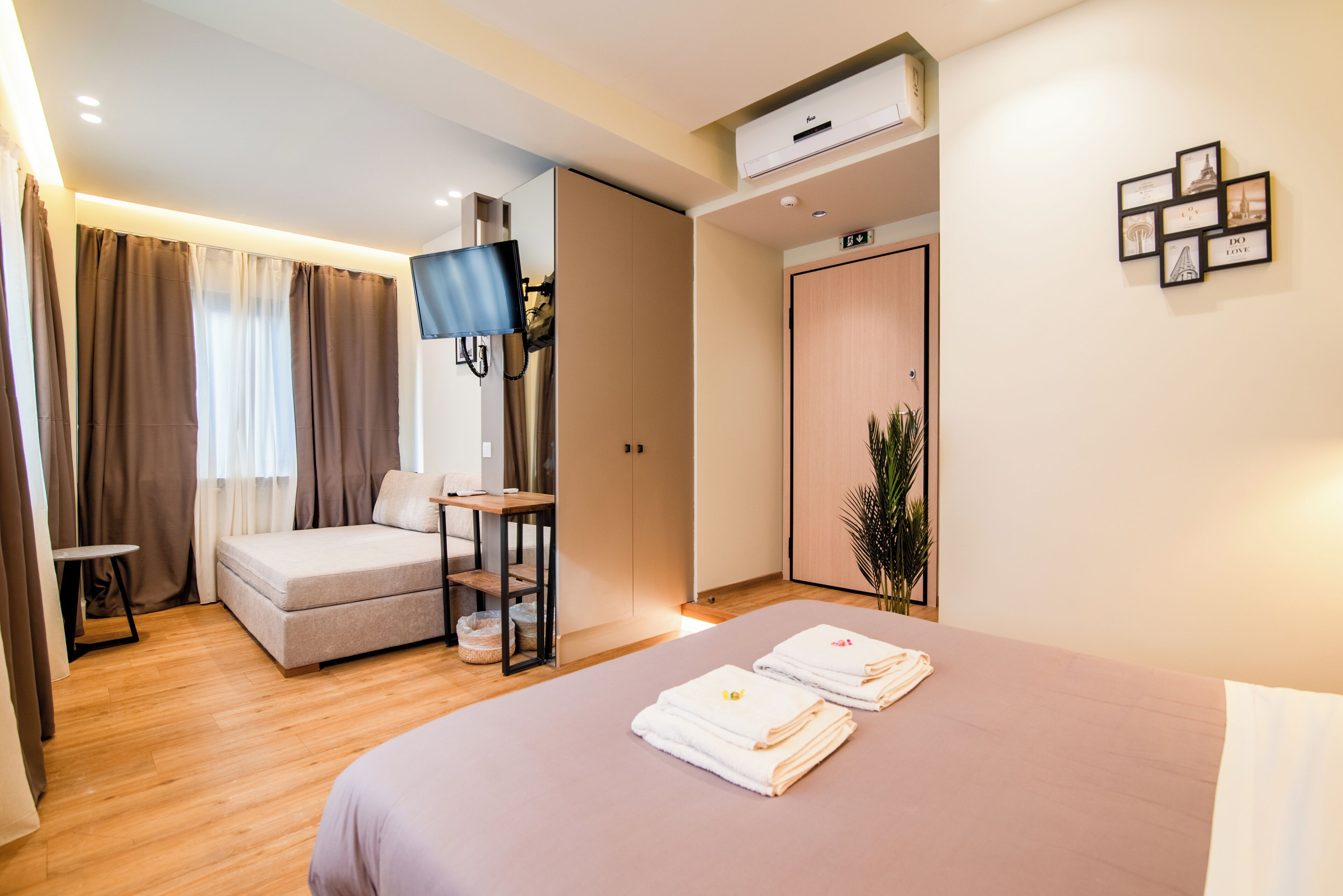 A modern hotel room with a bed, a sofa, a TV, and a desk.