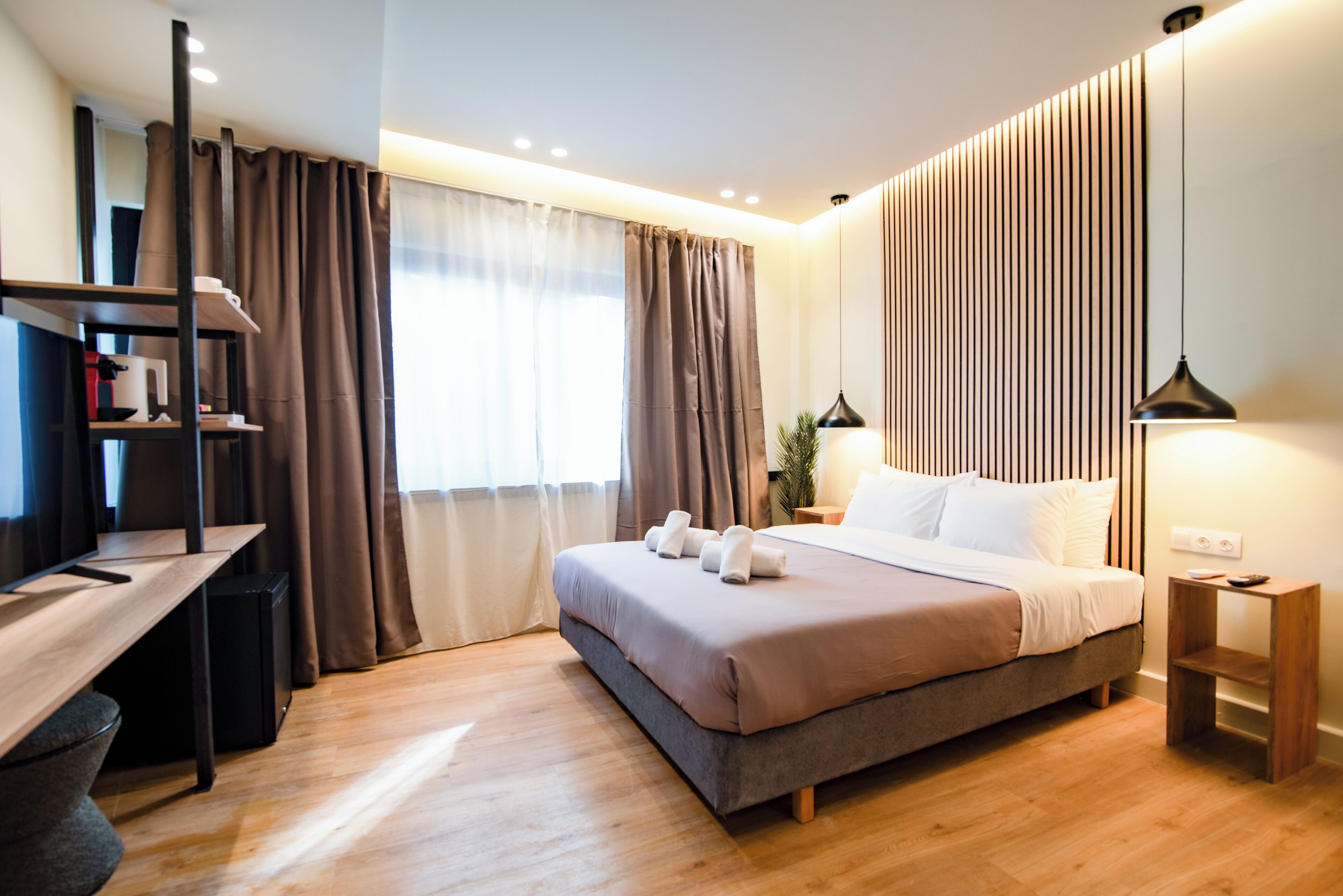 Quarto de hotel moderno com cama, escrivaninha e cortinas.