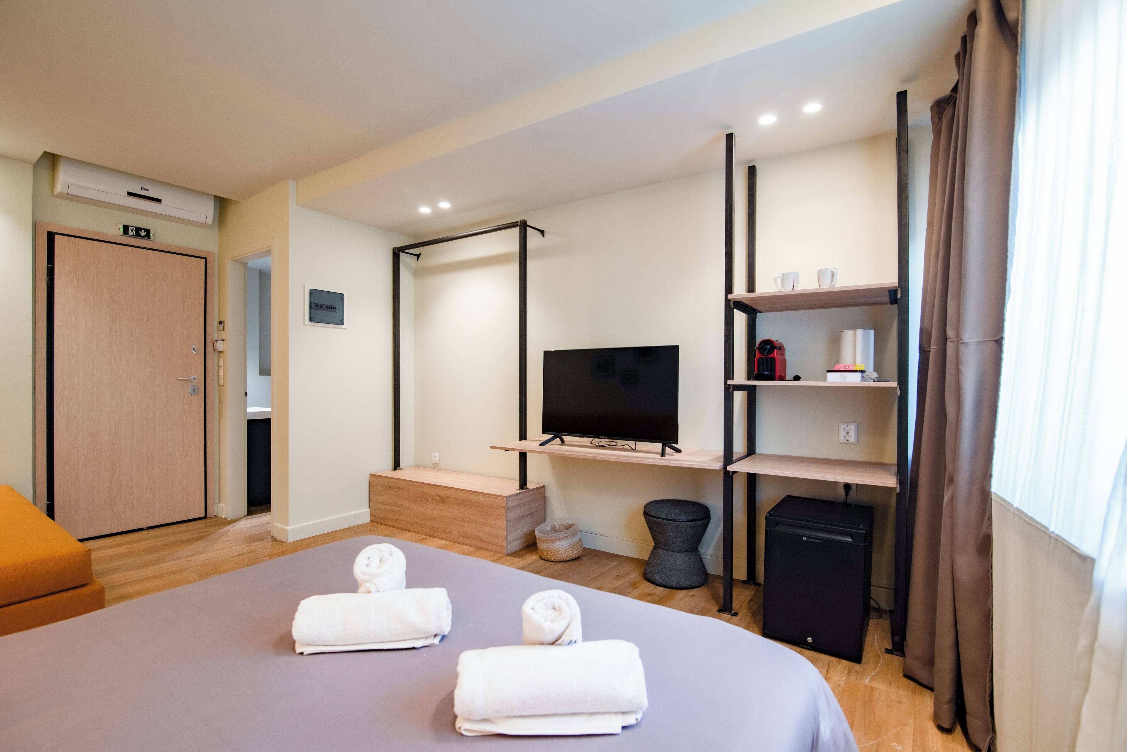 A hotel room with a bed, a TV, a desk, a wardrobe, and a bathroom.