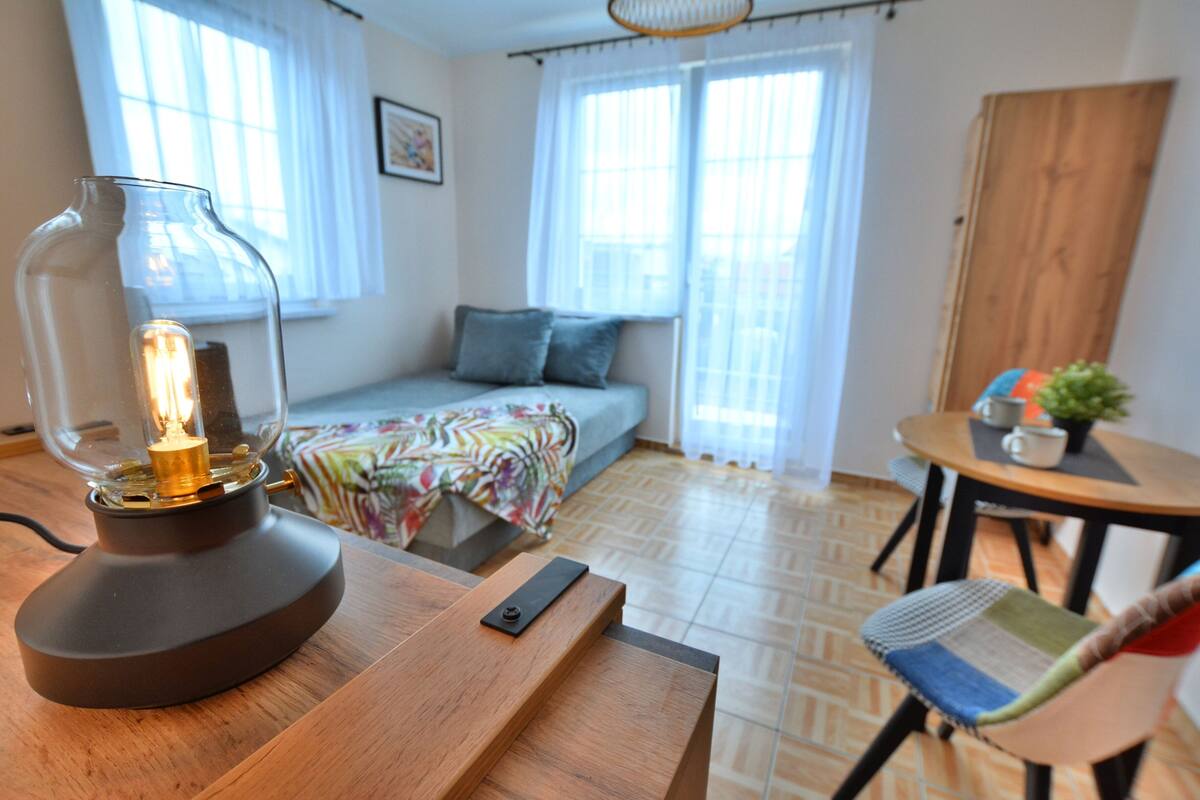 Ein modernes Wohnzimmer mit einer Couch, einem Tisch mit Lampe und einem Sessel.