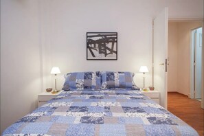 A bedroom with a bed, two bedside tables, a wall-mounted artwork, and a door leading to another room. - Departamento Arenales 2A (Buenos Aires)
