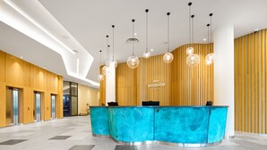 A reception area with a blue counter, wooden panel walls, and a tiled floor. - Seaside Park Hotel (Kolobrzeg)