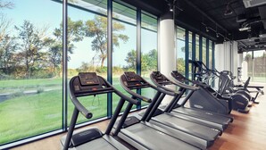A gym with treadmills, exercise bikes, and a view of a green landscape through large windows. - Seaside Park Hotel (Kolobrzeg)