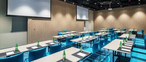 Un salón de conferencias con varias mesas y sillas, equipado con botellas de agua y tarjetas de identificación.