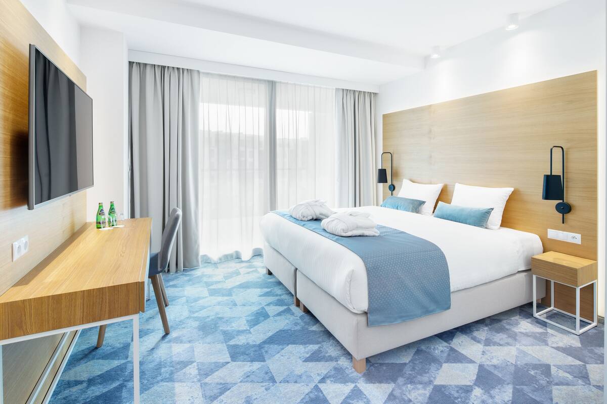 Une chambre d’hôtel moderne, dotée d’un grand lit, d’un bureau et d’une télévision.