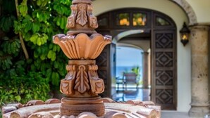 A stone fountain with intricate carvings in a garden setting. - Cabocasabuenavista- WALK TO Private Beach. Roof top deck.  Pets welcome (San Jose Del Cabo)