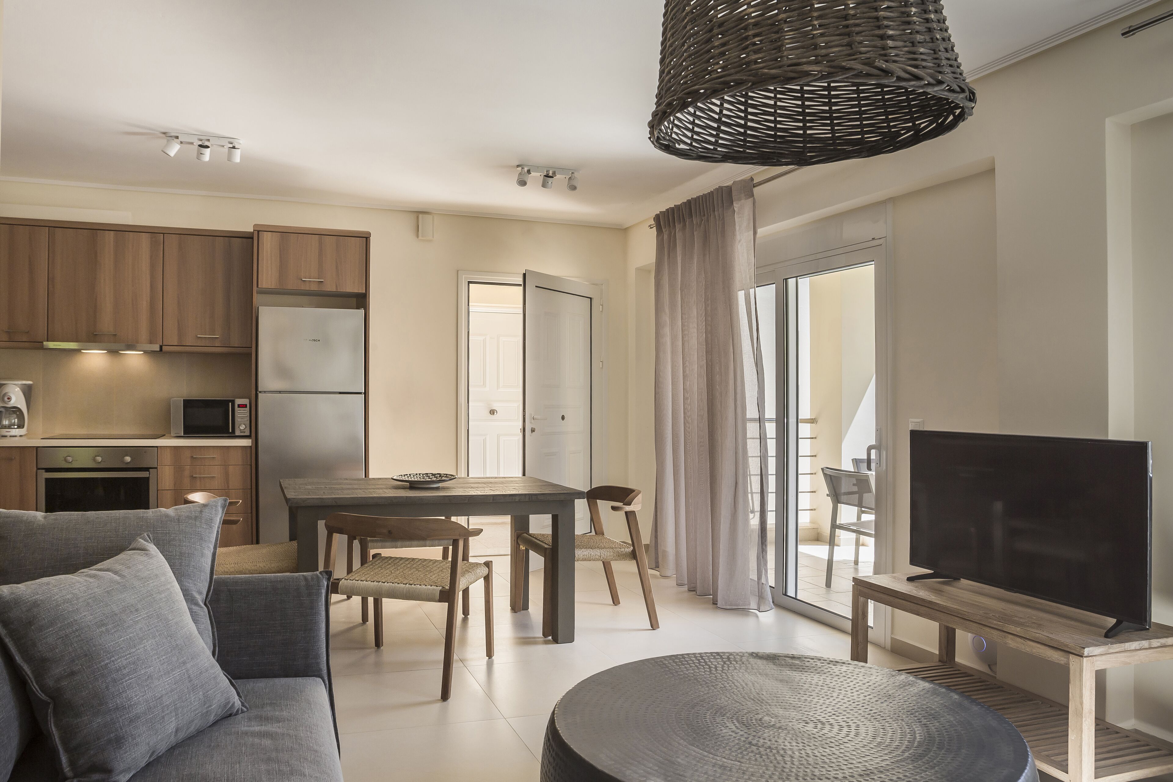 A modern living room with a sofa, TV, dining table, and kitchen area.
