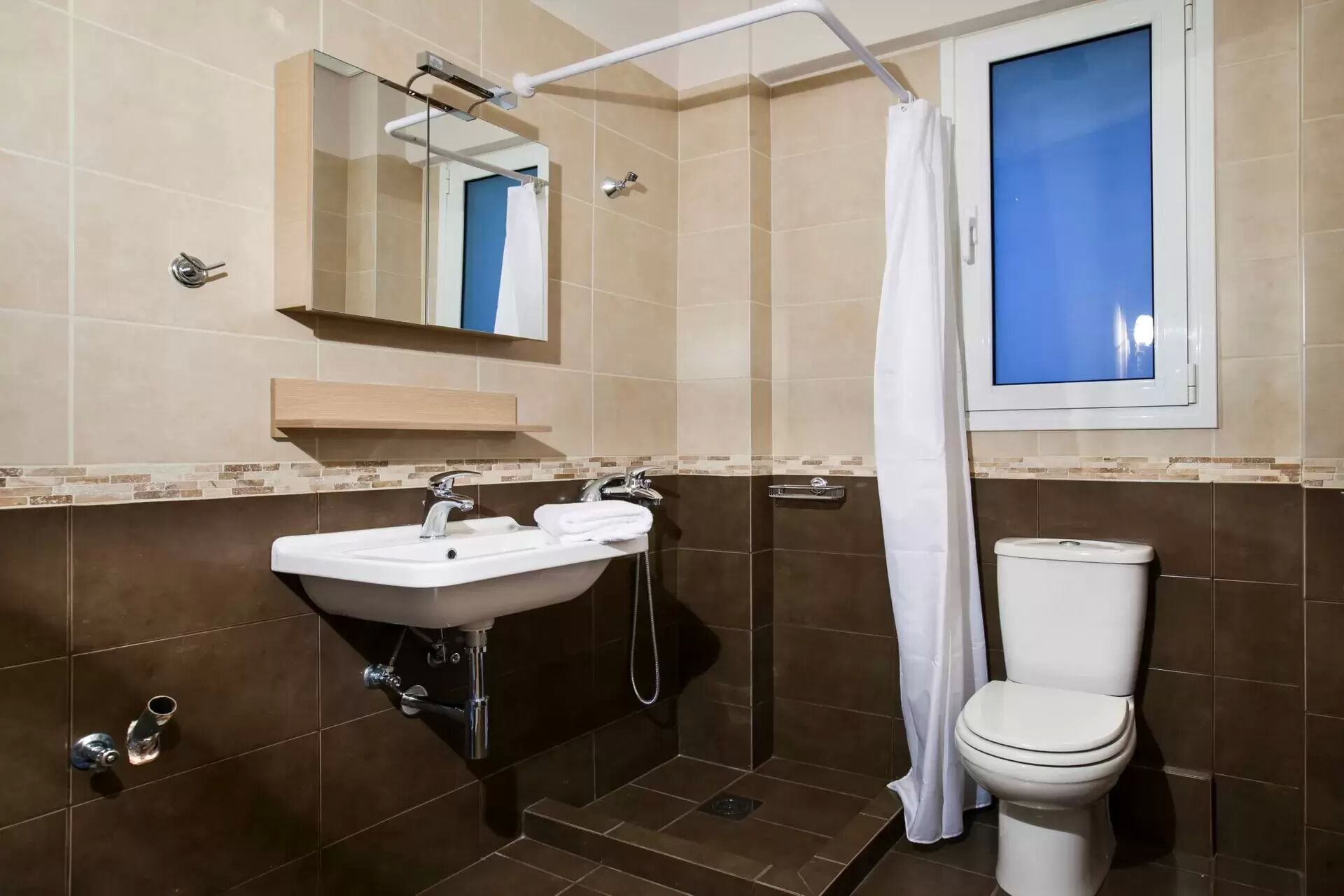 Een badkamer met een wastafel, spiegel, toilet en douchegordijn.