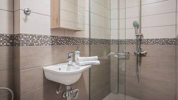 A modern bathroom with a glass shower enclosure, a sink with a mirror, and a tiled backsplash.