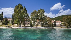 A coastal hotel with multiple buildings, a beach, and clear turquoise water. - Meliti Waterfront Suites (Kefalonia)