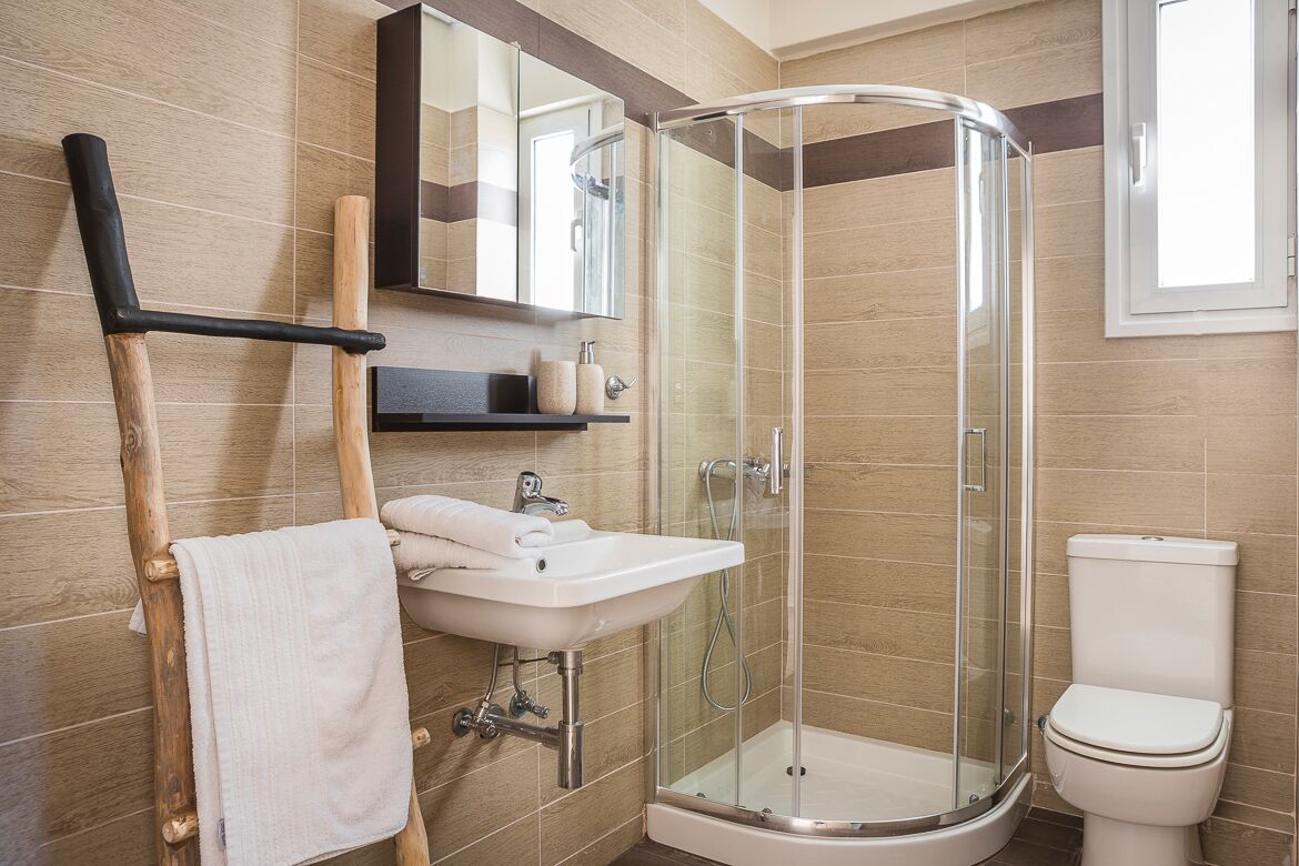 Ein modernes Badezimmer mit einer Duschkabine aus Glas, einem weißen Waschbecken und einer Toilette.