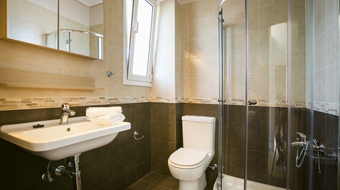 A bathroom with a sink, toilet, and glass-enclosed shower area.