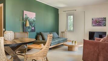 A modern living room with a green accent wall, a sofa, a coffee table, and a TV.