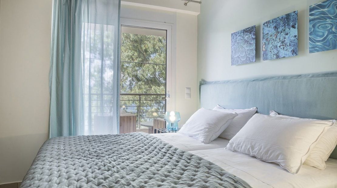 Une chambre à coucher comprenant un lit, une tête de lit, une table de chevet et une fenêtre avec des rideaux.