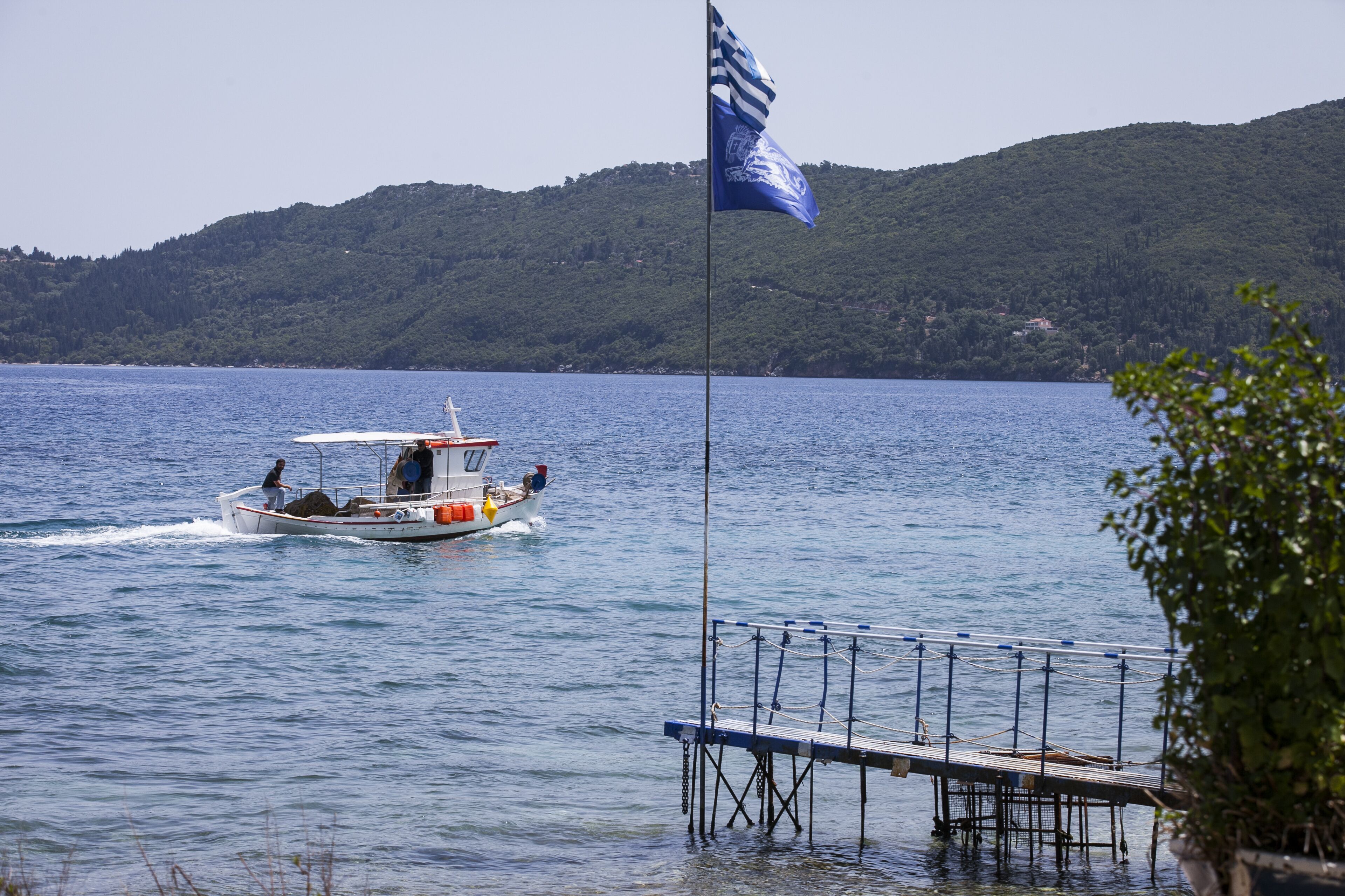 A boat on a lake with a dock and a flag.