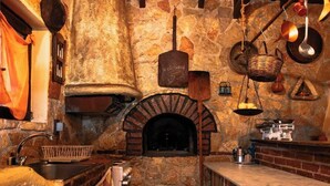 Una cocina rústica con pared de piedra, techo de madera y horno de ladrillo.