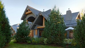 Une maison moderne avec un toit en pente, de grandes poutres en bois et un jardin bien entretenu.