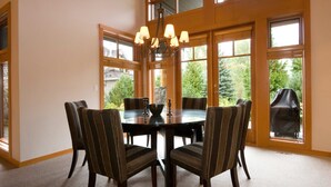 Un coin repas avec une table ronde, six chaises et un lustre.