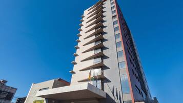 Un moderno edificio de gran altura con una entrada destacada y una bandera visible.