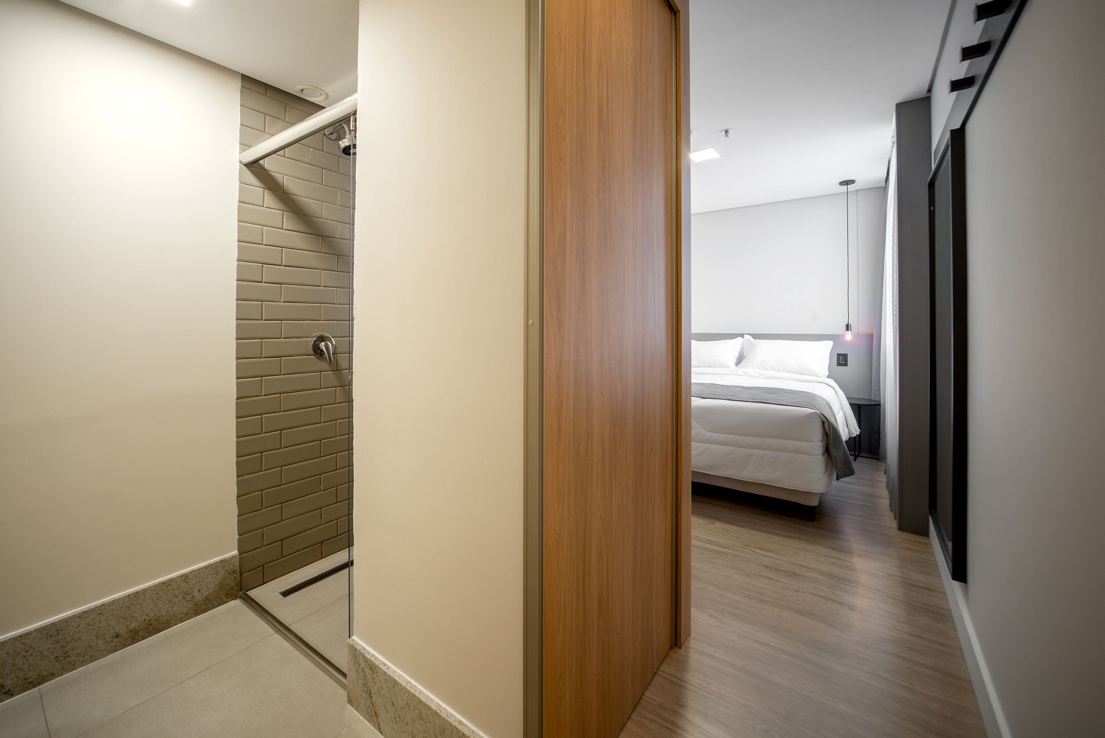 Una habitación de hotel moderna con ducha, cama y armario de madera.