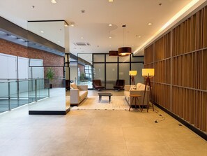 Un vestíbulo moderno con separador de vidrio, zona de estar y paneles de madera.