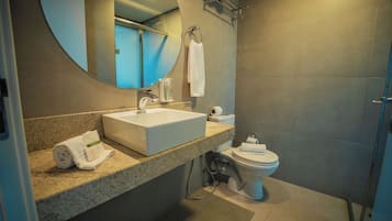 Un baño moderno con encimera de granito, un lavamanos blanco, un inodoro y un espejo.