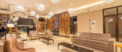 A modern lobby with a sofa, chairs, a coffee table, and unique spherical pendant lights.