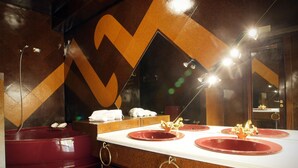 Ein modernes Badezimmer mit einem großen Spiegel, drei Waschbecken und einer roten Badewanne.
