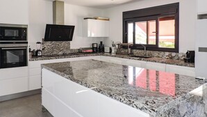 A modern kitchen with granite countertops, built-in appliances, and a large window providing natural light.