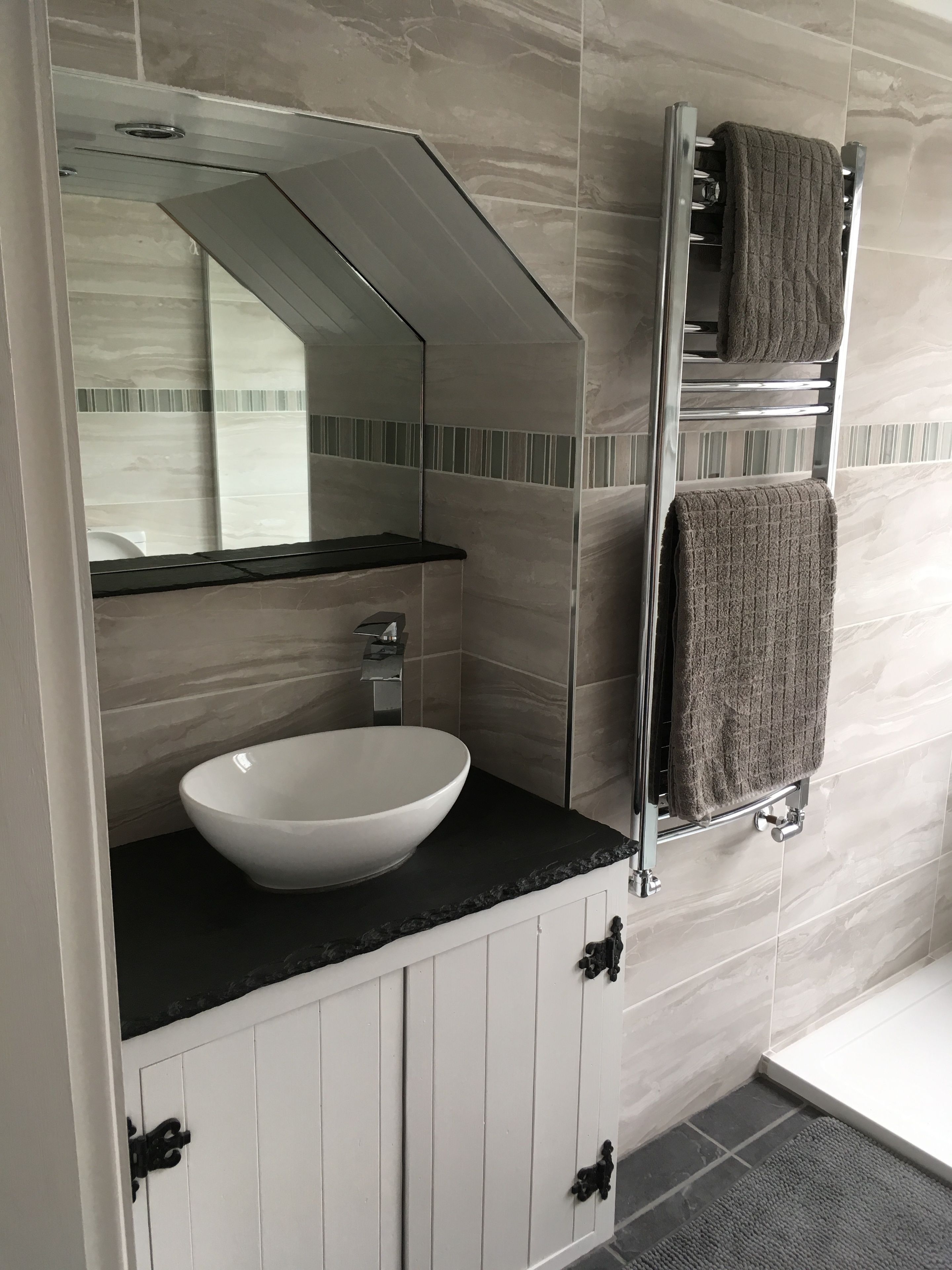 A bathroom with a white sink, a mirror, a towel rack, and a shower area.