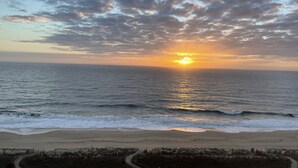 A beach with a sunset over the ocean, sandy shore, and sparse vegetation. - Beach Front with Amazing Views from Oceanside & Bayside (Ocean City)