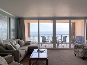 En rummelig balkon med havudsigt, møbleret med en sofa, stole og et bord.