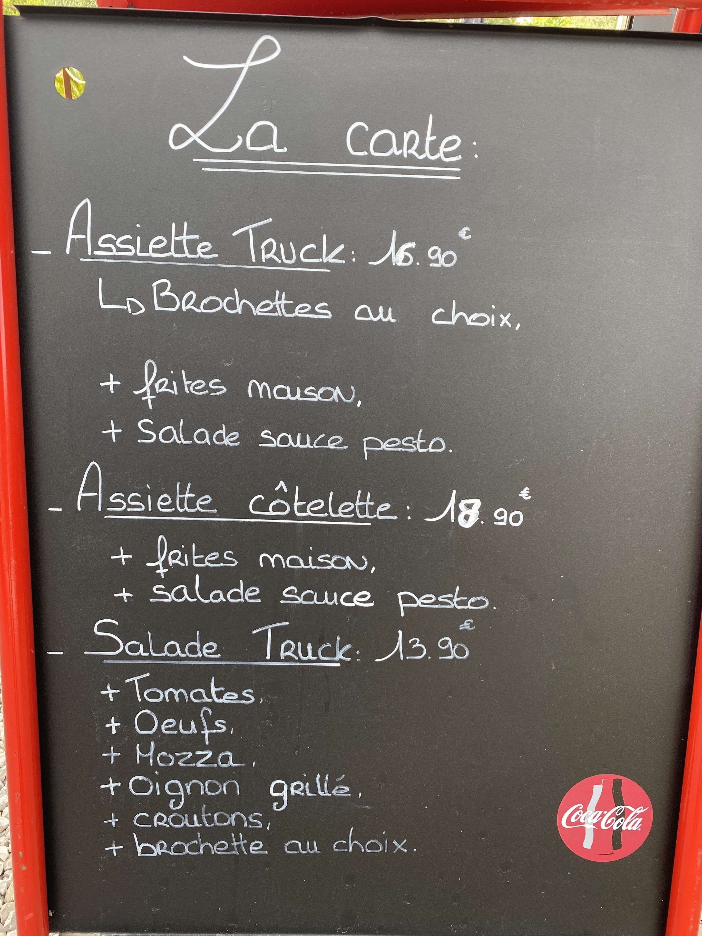 Een krijtbord met een menu, waarop gerechten en prijzen staan.