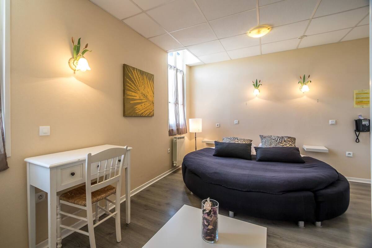 Een slaapkamer met een bed, nachtlampjes, een bureau en een stoel.